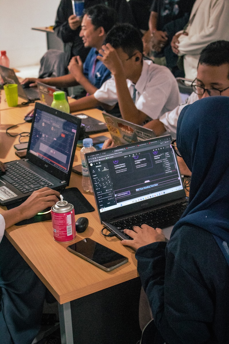 Students working on laptops at a shared desk.